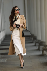 a lady wears a midi skirt with a belt and a scarf on neck